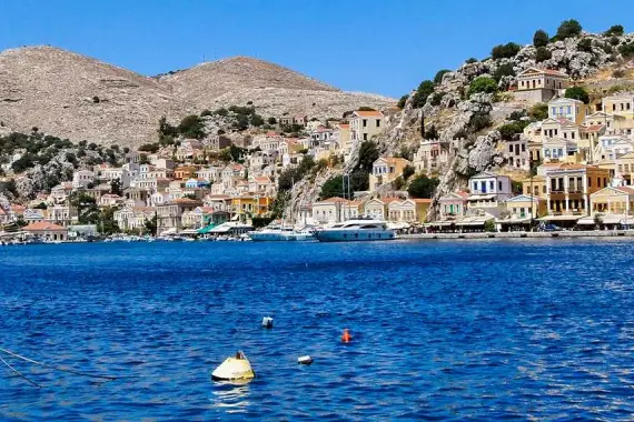 Isola di Tilos, nel Dodecaneso: panorama dal mare con barche e cittadina sullo sfondo